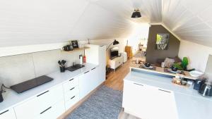 a kitchen with white cabinets and a living room at Lorraine Loft Apartment in Gqeberha