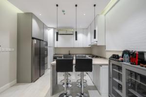 a kitchen with white cabinets and black stools at رواء آن للضيافة in Quai