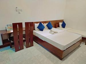 a bedroom with two beds with blue pillows and a desk at Jegers Villa in Negombo