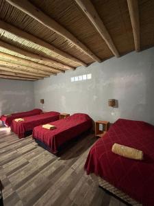 a room with three beds with red sheets on them at Hospedaje Don Carmelo in El Peñón