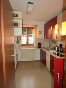 a kitchen with brown cabinets and a sink and a window at Barrierefreie Ferienwohnung Bodenseeblick in Unteruhldingen