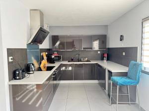 a kitchen with a counter and a blue chair at Big Flat - Direct CERN in Saint-Genis-Pouilly