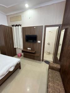 a bedroom with a bed and a television and a bathroom at Hotel Royale Elite RK Residency in Vrindāvan