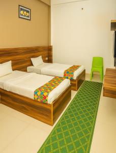 a bedroom with two beds and a green chair at Hotel Royale Elite RK Residency in Vrindāvan