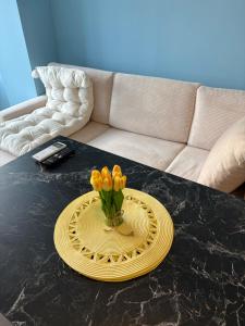 a vase of flowers on a table in a living room at Апартамент център Поли in Sandanski