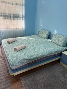 a bed with two pillows on it in a room at Апартамент център Поли in Sandanski