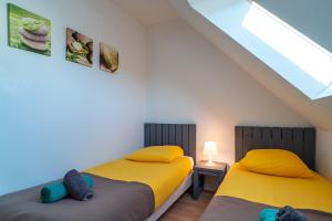 two twin beds in a room with a skylight at Pentrez Cottage - 600m de la Plage in Saint-Nic