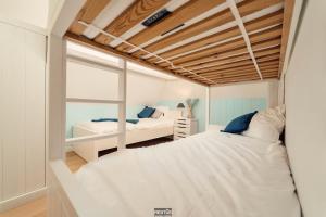 two beds in a small room with a window at Villa Promenade - luxuriously apartment for 8 people in Nieuwpoort