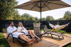 a man and woman sitting in chairs under an umbrella at Boutique Hotel, Restaurant & Wellness Westerburcht in Westerbork