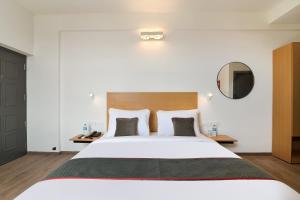 a bedroom with a large white bed and a mirror at Townhouse Srm Kuppakonam Pudur in Coimbatore