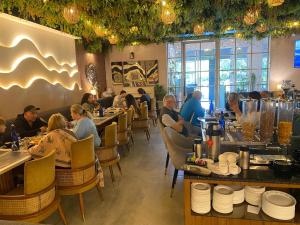 a group of people sitting at tables in a restaurant at Hotel Pallavi Grand in Panchkula