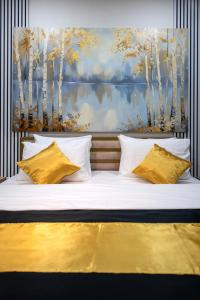 a bed with yellow pillows and a painting of trees at Hotel Centar Sanski Most in Sanski most