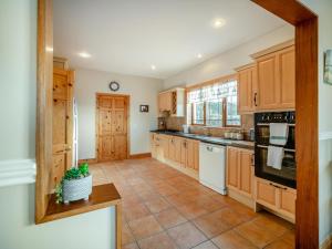 a kitchen with wooden cabinets and a tile floor at 3 Bed in Renvyle oc-i254 in Cashleen