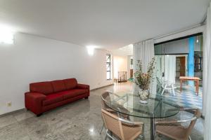 a living room with a glass table and a red couch at Rio´s Mansion: Sugar Loaf, The Redeemer and Pool in Rio de Janeiro