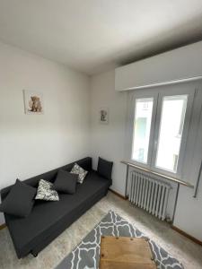 a living room with a black couch and two windows at Casa Bice in Misano Adriatico +1 photo