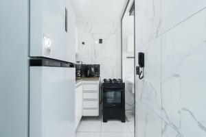a white kitchen with a stove and a refrigerator at Condominio da Americas Maspex in São Paulo