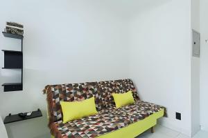 a couch with two yellow pillows in a room at Condominio da Americas Maspex in São Paulo