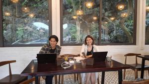 two people sitting at a table with laptops at Chinh Thu Garden Retreat in Ninh Binh