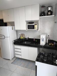 a kitchen with white cabinets and a sink and a microwave at Apartamento Jacumã -Conde-PB in Conde