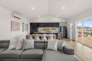 a living room with a gray couch and a kitchen at Allawah in Encounter Bay