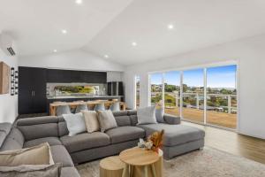 a living room with a gray couch and a kitchen at Allawah in Encounter Bay