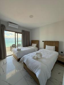 two beds in a bedroom with a view of the ocean at Golden Bay Hotel in Al Hoceïma +1 photo