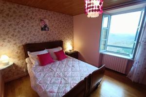 a bedroom with a bed with pink pillows and a window at La bellevue in Lapeyrugue
