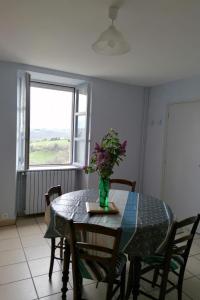 a dining room table with a vase of flowers on it at La bellevue in Lapeyrugue +5 photos