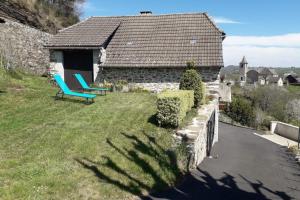 a house with two blue chairs in the yard at La bellevue in Lapeyrugue