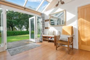 a conservatory with a chair and a mirror at Heather Barn in Saltash +5 photos