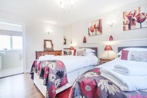 two beds in a bedroom with white walls at Heather Barn in Saltash