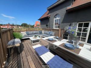 a wooden deck with a couch and a table at Villa Promenade - luxuriously apartment for 8 people in Nieuwpoort