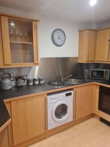 a kitchen with a washing machine and a clock on the wall at Gorgeous Marina 2 Bed Apartment in Portishead