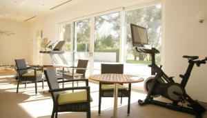 a room with a gym with a treadmill and a table and chairs at Hubertus Hof Landhotel in Balatonfenyves