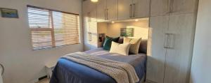 a bedroom with a bed with blue sheets and a window at Little Nest One Bedroom Apartment! in Knysna