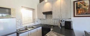 a kitchen with white cabinets and a black counter top at Little Nest One Bedroom Apartment! in Knysna +10 photos