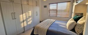 a bedroom with a bed and cabinets and a window at Little Nest One Bedroom Apartment! in Knysna