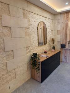 a stone wall with a vanity and a mirror at Studio chaleureux, massage, terrasse privé, barbecue et balneo in Cussac-Fort-Medoc +17 photos