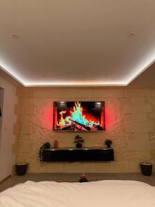 a tv mounted on a brick wall with a fireplace at Studio chaleureux, massage, terrasse privé, barbecue et balneo in Cussac-Fort-Medoc