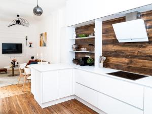 a kitchen with white cabinets and a wooden wall at Altstadt Geverdes 1 in Lübeck