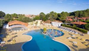 a resort with a large swimming pool with lounge chairs at MH J08 - Camping Siblu La plage in Mimizan-Plage