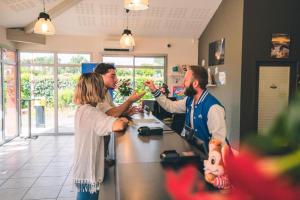 a group of three people standing at a counter eating food at MH J08 - Camping Siblu La plage in Mimizan-Plage