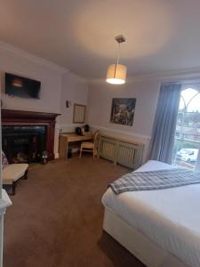 a bedroom with a bed and a desk and a fireplace at Fox and Pheasant Inn in Armathwaite