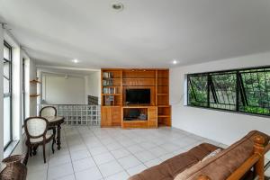a living room with a couch and a tv at Rio´s Mansion: Sugar Loaf, The Redeemer and Pool in Rio de Janeiro