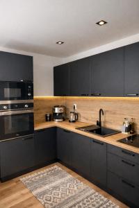 a kitchen with black cabinets and a sink at Modern Central Apartment in Nitra