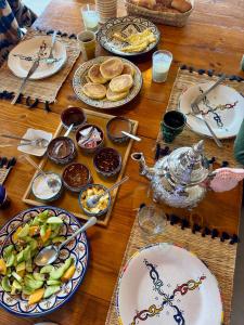 a wooden table with plates of food on it at Monza Surf House in Tamraght Ouzdar