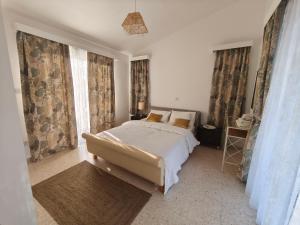 a bedroom with a bed and two windows with curtains at Villa Koralia in Peyia +31 photos
