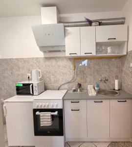a white kitchen with a microwave and a sink at Levendula Apartman in Bačka Topola +21 photos