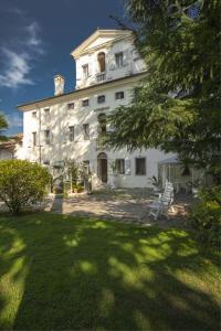 a large white building with two chairs in a yard at Villa Cigolotti in Vivaro