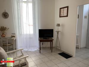 a living room with a television and a table at Echoppe Ancienne Boutique de cordonnier avec jardin privé in Aubeterre-sur-Dronne